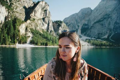 Portrait of young woman looking at lake against mountains