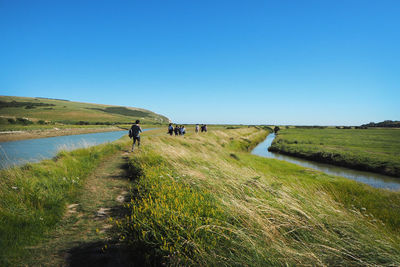 People walking on field against clear sky
