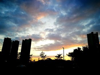 Low angle view of skyscrapers against cloudy sky