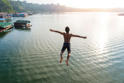 Rear view of shirtless man jumping in sea