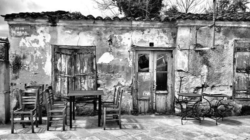 Empty chairs and table against old building