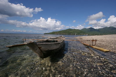 Boat moored on beach against sky