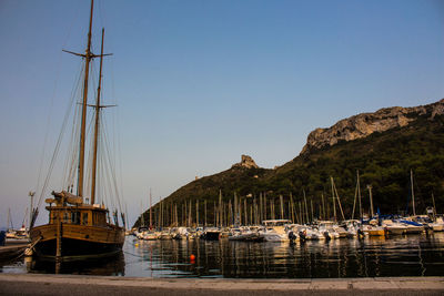 Boats moored at harbor against clear sky