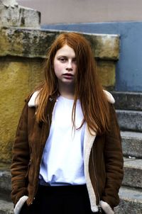 Portrait of young woman standing against steps