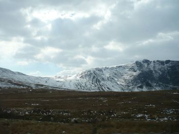 Scenic view of snow covered mountains against cloudy sky