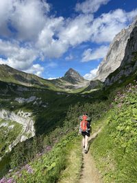 Low angle view of people walking on mountain against sky