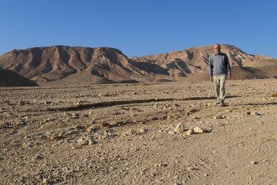 Senior man walking at desert against clear sky
