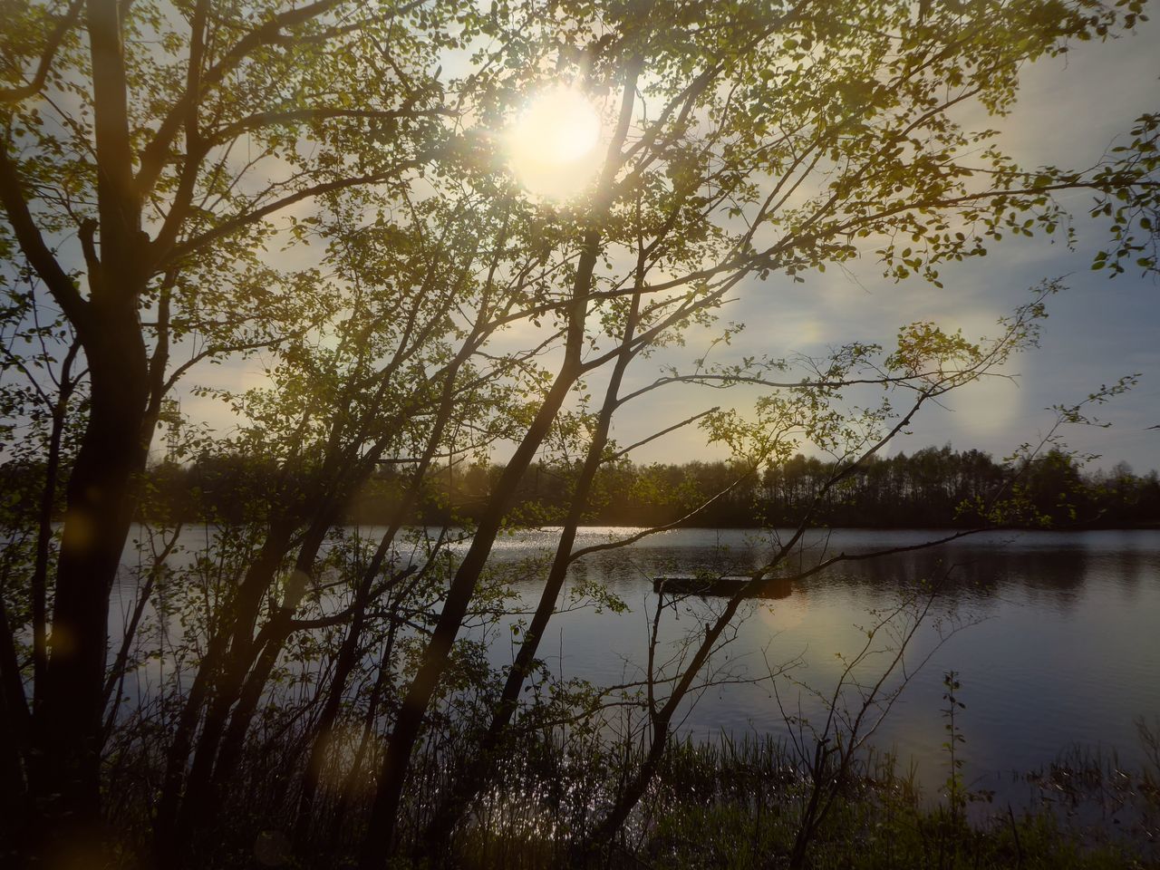 SCENIC VIEW OF LAKE AGAINST BRIGHT SUN DURING SUNSET