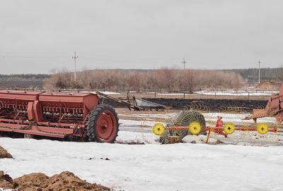 Abandoned railroad tracks on field against sky during winter