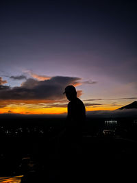 Rear view of silhouette man standing against sky during sunset