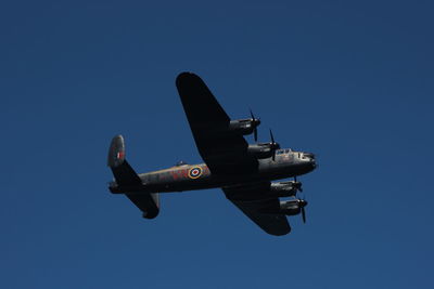 Low angle view of airplane against clear blue sky