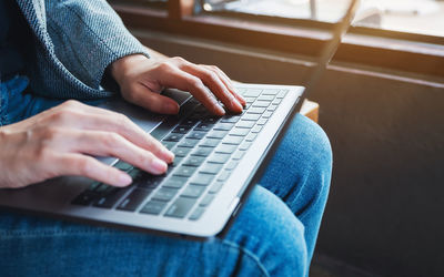 Midsection of woman using laptop on table