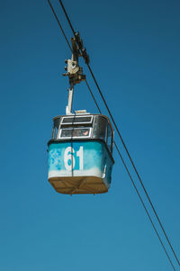 Low angle view of telephone pole against clear blue sky