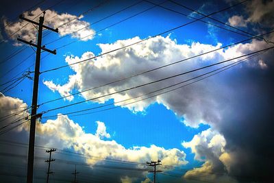 Low angle view of electricity pylon against cloudy sky