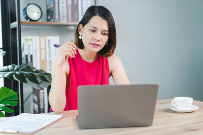 Mid adult woman using mobile phone while sitting on table