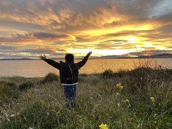 Man standing on field against sky during sunset