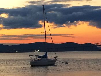 Boats sailing in sea against cloudy sky