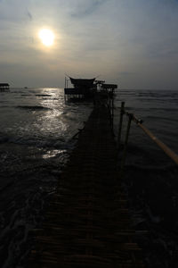 Pier over sea against sky during sunset