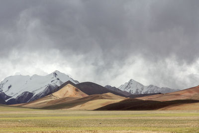 The beautiful barren yellow prairie at the foot of the snow mountain