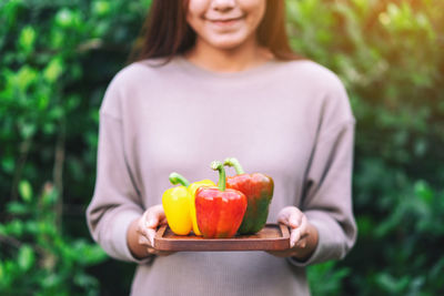 Midsection of woman holding strawberry while standing outdoors
