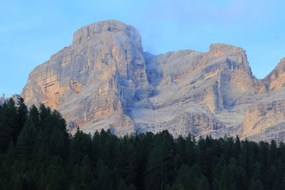 Low angle view of rocky mountain against blue sky