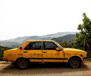 Yellow car on mountain road against clear sky