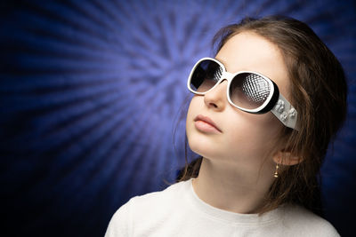 Close-up of girl wearing sunglasses against purple wall