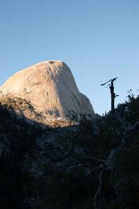 Low angle view of man standing on mountain against clear sky