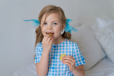 Portrait happy little caucasian girl eating crispy potato chips on gray