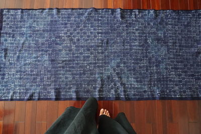 Low section of person standing by fabric on hardwood floor at home