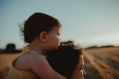 Mother with daughter on land against sky