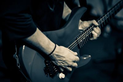 Midsection of man playing guitar
