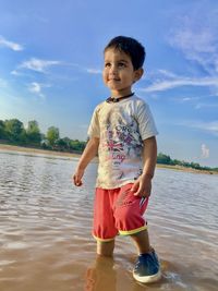 Cute boy in water against sky