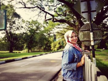 Portrait of mid adult woman wearing hijab standing on road against trees in park