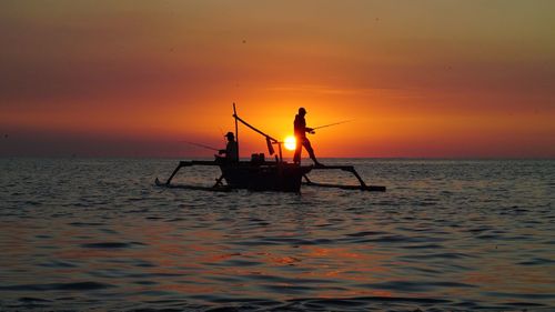 Silhouette boat in sea against orange sky