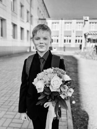 Portrait of happy boy with flowers in city