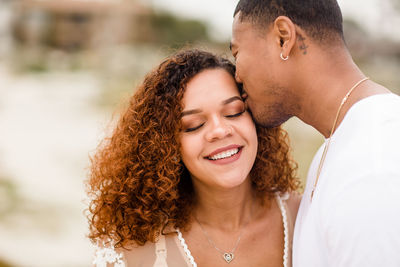 Husband embracing & kissing wife on beach