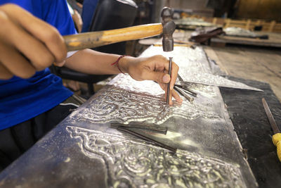 Midsection of woman carving metal