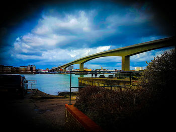 Bridge over river against cloudy sky