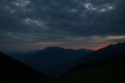 Scenic view of silhouette mountains against dramatic sky