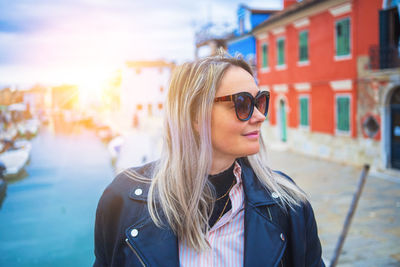 Portrait of young woman wearing sunglasses standing in city