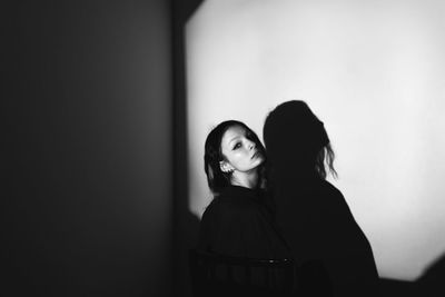 Portrait of young woman standing against wall