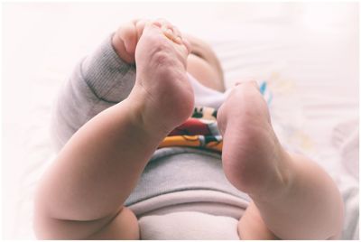 Low section of baby lying on bed