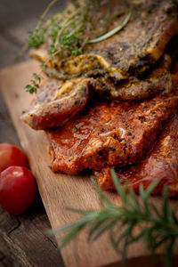 Cropped image of hand holding meat on cutting board