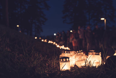 Close-up of lit tea light candles in forest at night