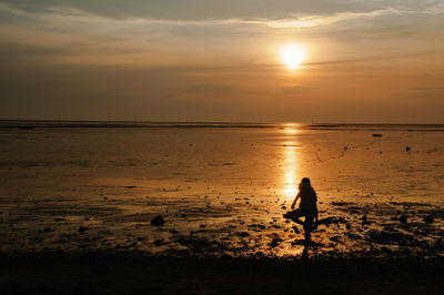 Silhouette man standing on beach against sunset sky