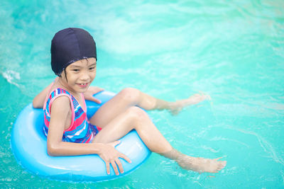 High angle view of smiling girl on inflatable ring in swimming pool