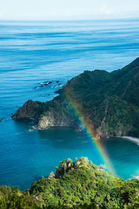 High angle view of rainbow against mountains and sea