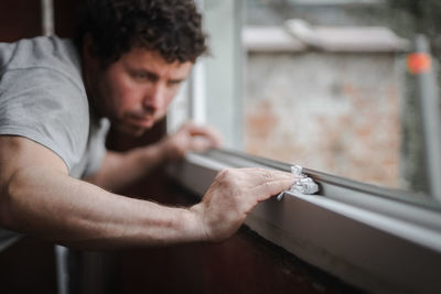 Caucasian man cleans the window frame.