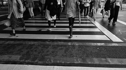 Low section of people walking on zebra crossing